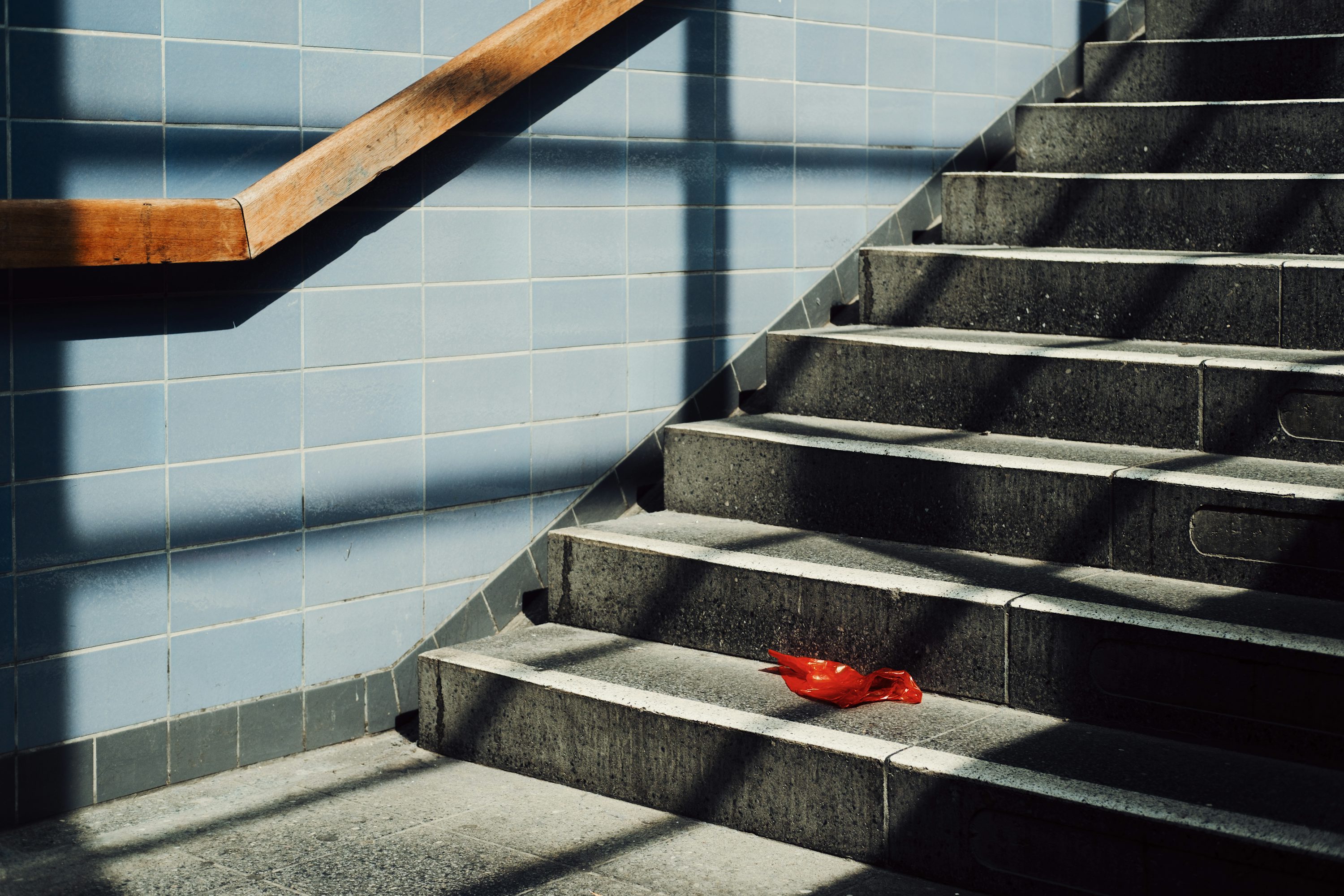 Un seul objet rouge repose sur un escalier ensoleillé.