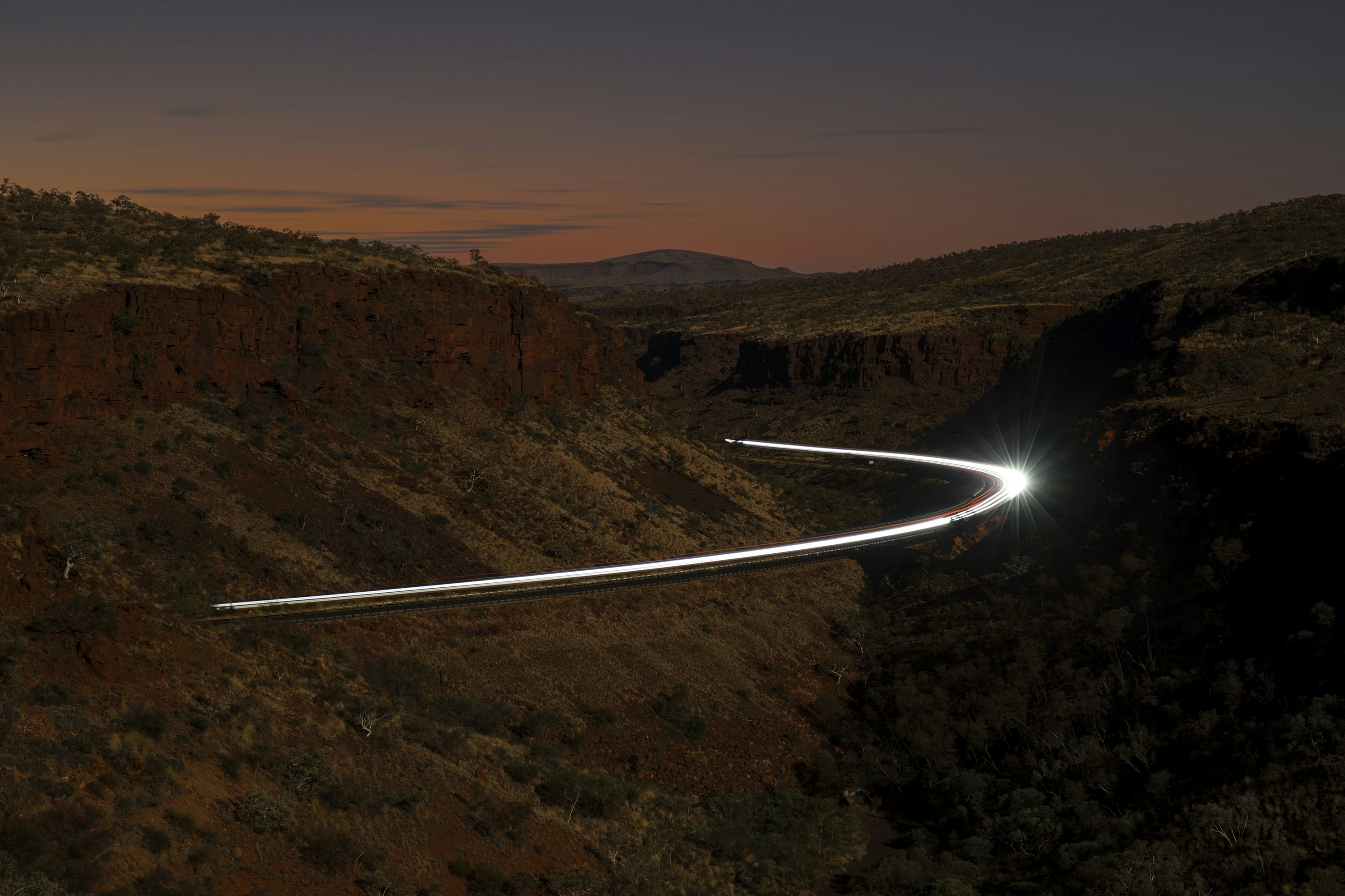 Traînées lumineuses de voiture à travers un canyon au crépuscule